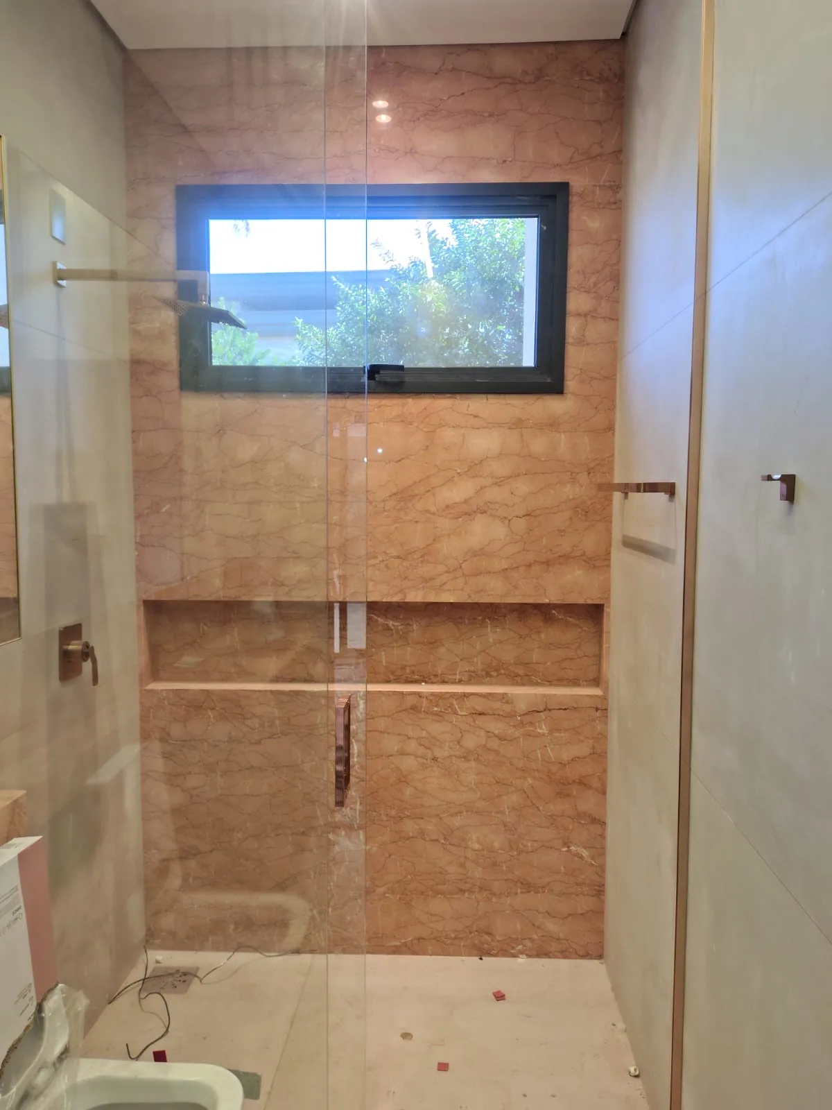 Detalhe de box de banho em marmore Rosa Portugues com nicho embutido recortado na propria pedra